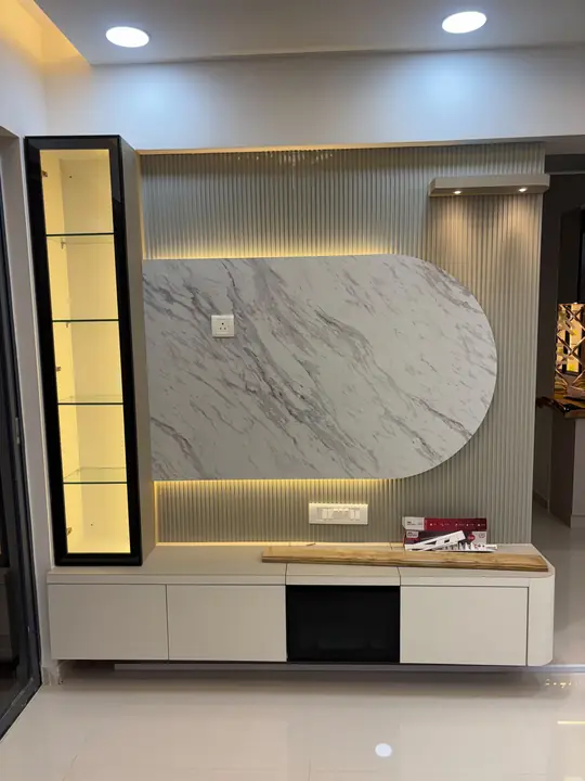 TV wall with oval marble panel, fluted slats and lit glass cabinet – VS Interiors, Wagholi